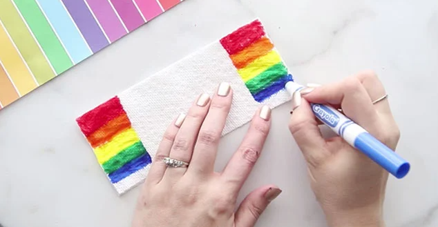 Mão pintando um papel toalha com canetinha colorida
